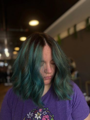 Person with teal hair looking down.