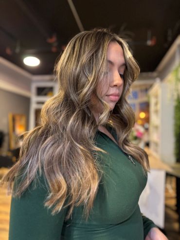 Woman with long, wavy blonde hair and green top.