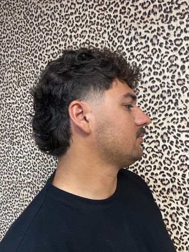 Profile of a man with curly hair against leopard print background.