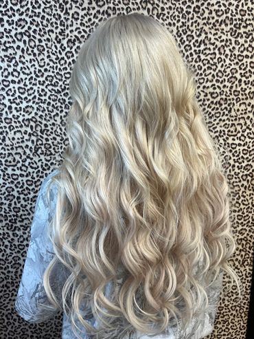 Long blonde wavy hair against a leopard print background.
