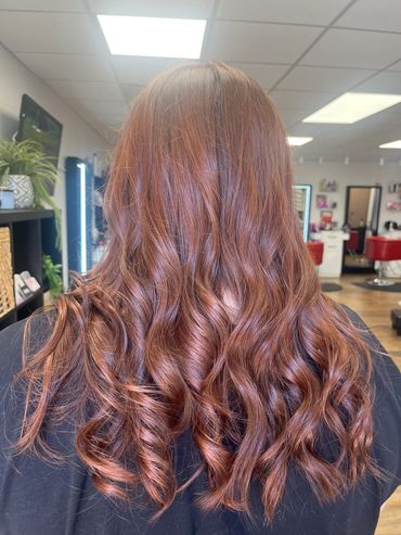 Long, wavy reddish-brown hair styled in loose curls.