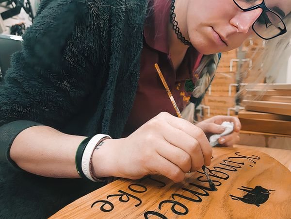 Gemma hand painting a large oak sign