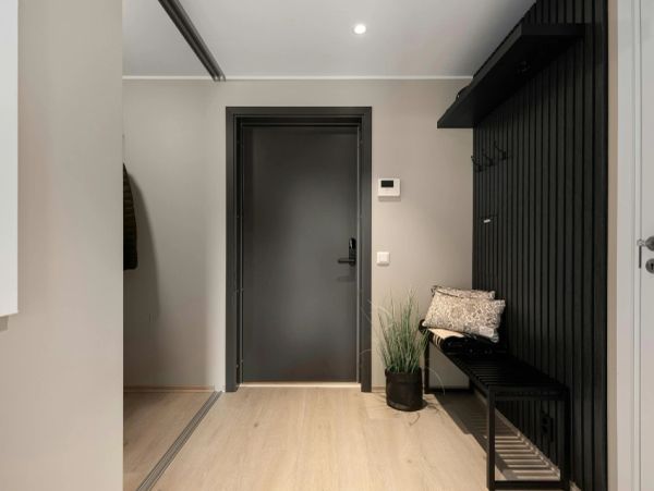 Minimalist entryway with black door and bench.