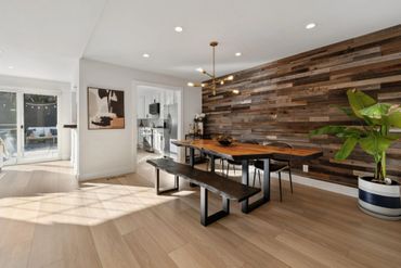 Modern dining area with wooden table, bench, and textured wood accent wall.