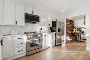 Bright modern kitchen with white cabinets and stainless steel appliances.