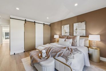 Cozy bedroom with neutral tones, sliding barn doors, and soft lighting.
