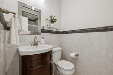 Small bathroom with dark wood vanity and decorative tile border.