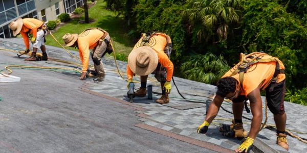 Workers installing shingles on a roof.