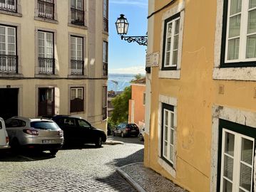 Picture of a winding street in the Alfama neighborhood on a sunny day,