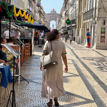 Picture of a young woman walking down Rua Augusta in Lisbon. She has her back to the viewer