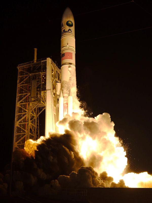 A rocket launching at night with bright flames and smoke.