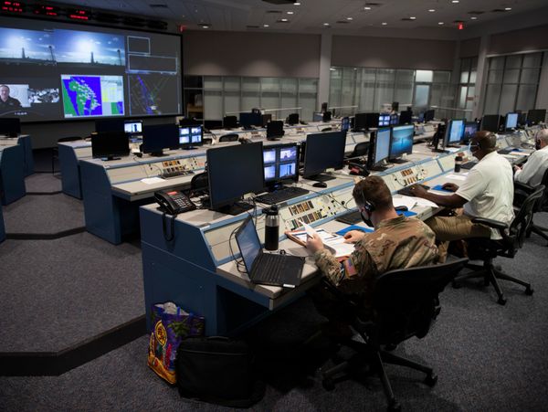 Military personnel working in a high-tech command center with multiple monitors.