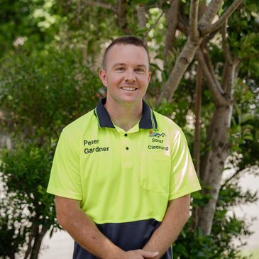 Man wearing a bright yellow and navy work shirt standing outdoors.