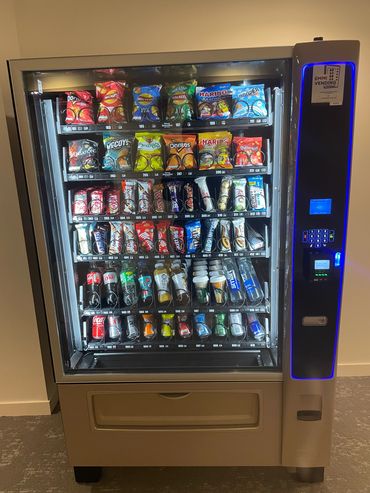 Snack and drink vending machine stocked with chips, chocolates, and beverages.