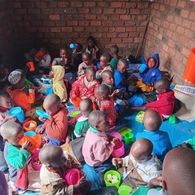 Children eating together in a brick-walled room.