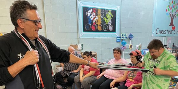 A man engaging a group in a creative exercise activity using resistance bands.