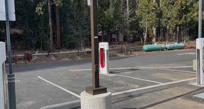 Empty Tesla charging station in a forested area.