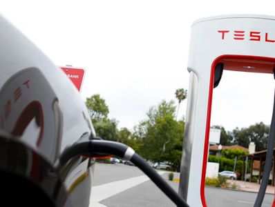 Tesla electric car charging at a Supercharger station outdoors.