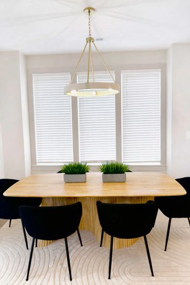 Modern dining room with wooden table, black chairs, and pendant light.