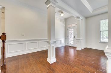 Entryway with dark hardwood floors, white walls, white columns, and wainscoting.