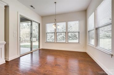 Empty room with dark hardwood floors, white walls, and large windows with blinds.