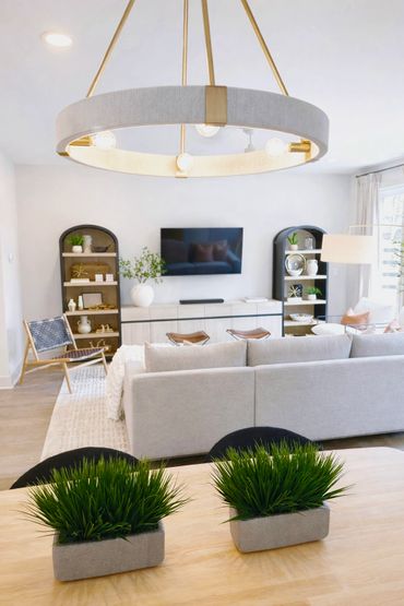 Modern living room with neutral tones, greenery, and stylish lighting.