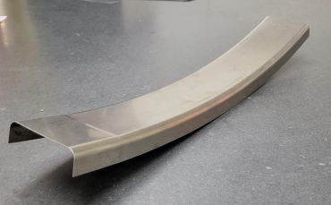Curved metal bracket with a shiny finish on a gray surface.