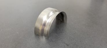 A shiny metal curved object on a dark surface.