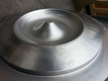 A shiny metallic conical and circular object on a rough surface.