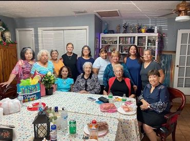 Group of women gathered around a table for a celebration in a cozy room.