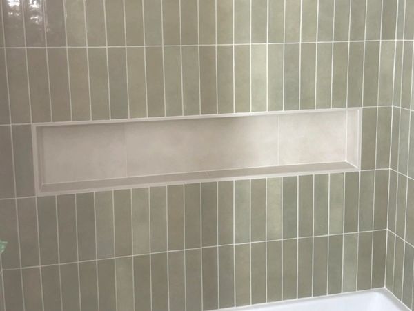 Empty recessed shelf in tiled bathroom wall.