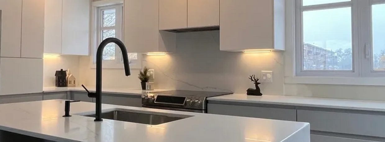 Modern kitchen with white countertops and black fixtures.