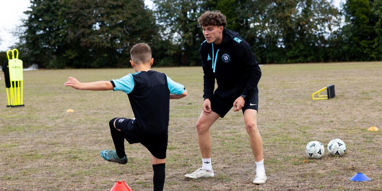 Soccer coaching session with a child and coach on a field.