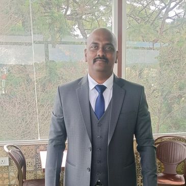 Man in a formal grey suit standing on green artificial grass.