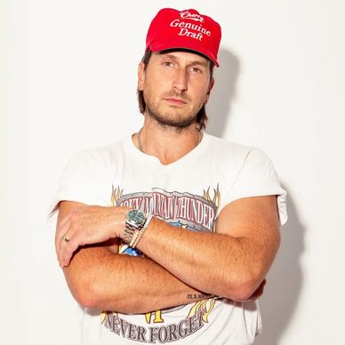 Man wearing a red cap and vintage band t-shirt, arms crossed.