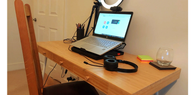 Laptop, headphones and ring light on a desk. My online therapy space.