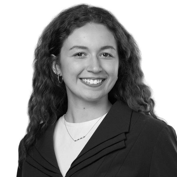 Professional black and white headshot of a smiling woman with curly hair.