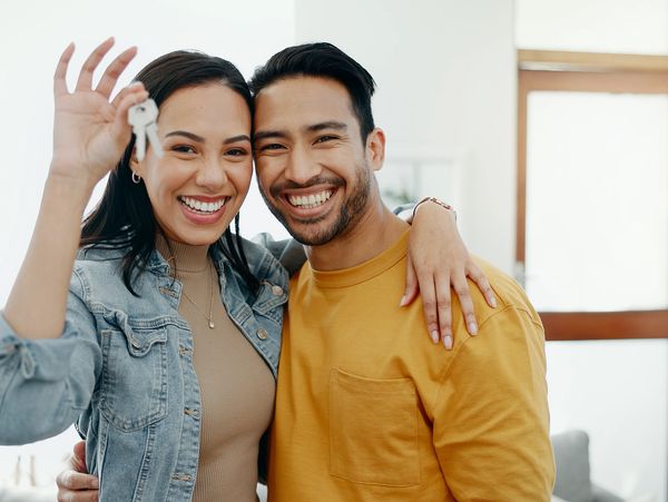 A joyful couple smiling and holding up keys to their new home.