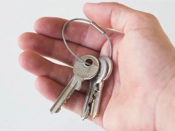 A person's hand holding a set of keys on a ring.