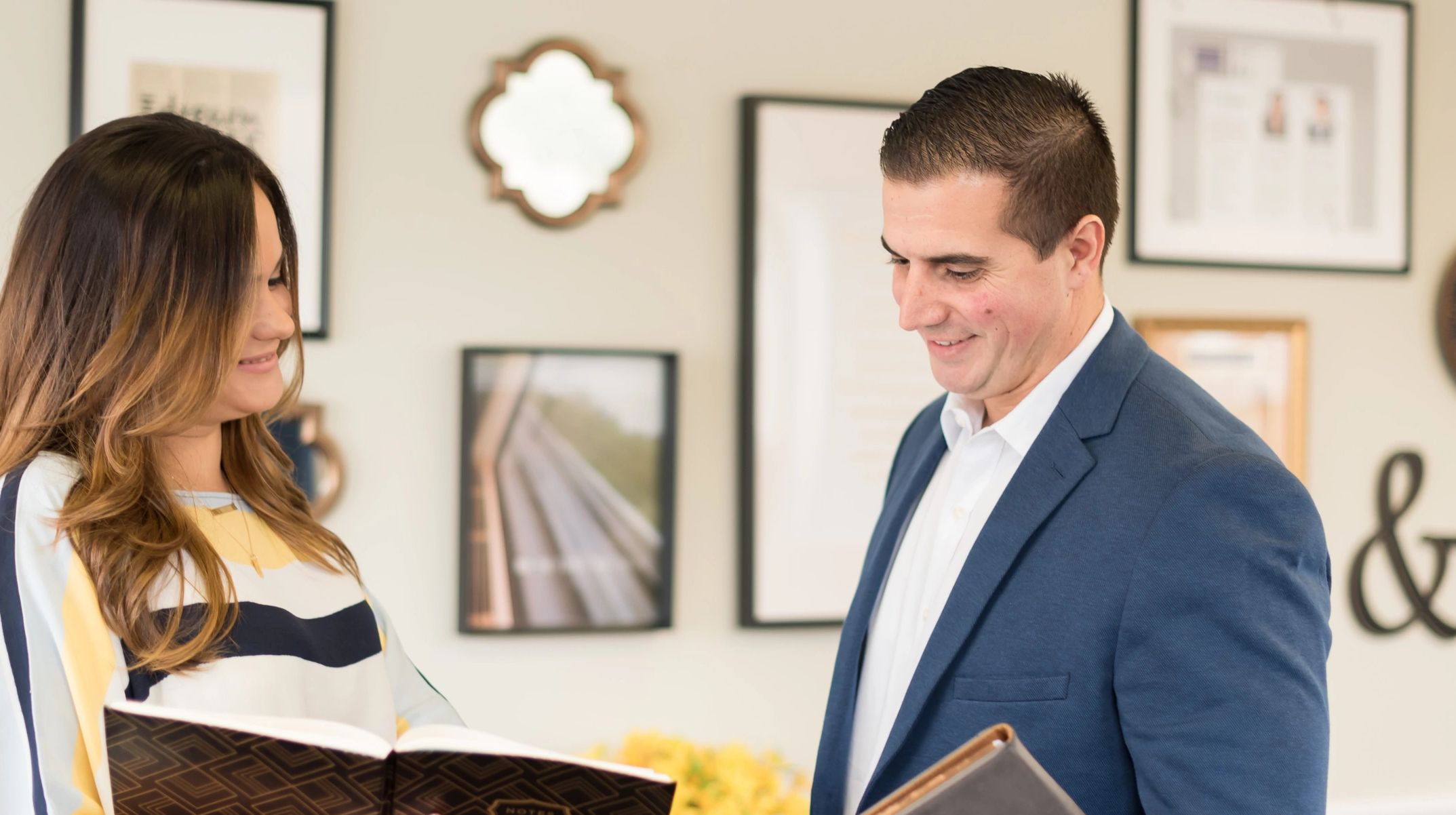 Two people reviewing a notebook while smiling.