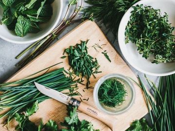 Fresh herbs on a cutting board with a knife.