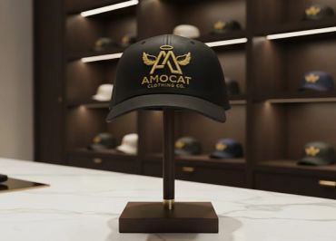 Black cap with gold AMOCAT logo on display stand.