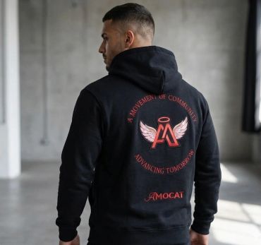 Man wearing a black hoodie with a winged logo and text on the back.