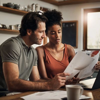 Couple reviewing documents together at home with a laptop.
