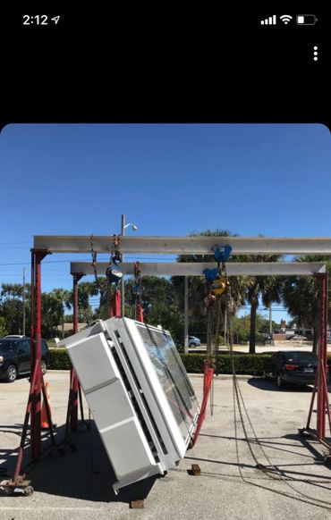 A large metal frame lifting a heavy industrial unit outdoors on a sunny day.