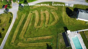 Aerial view of Nature's Getaway RV Park with mown grass pathways and a swimming pool.