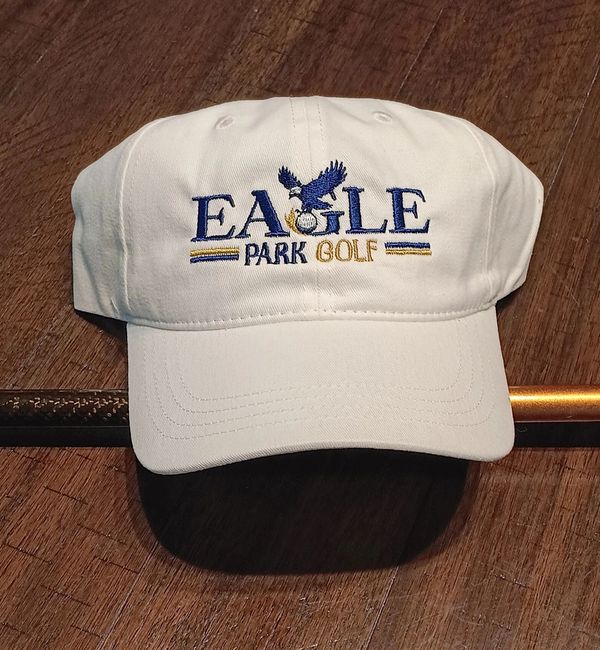 White golf cap with embroidered "Eagle Park Golf" logo on wooden surface.