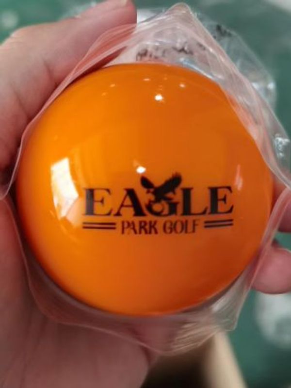 Close-up of an orange golf ball with Eagle Park Golf logo.