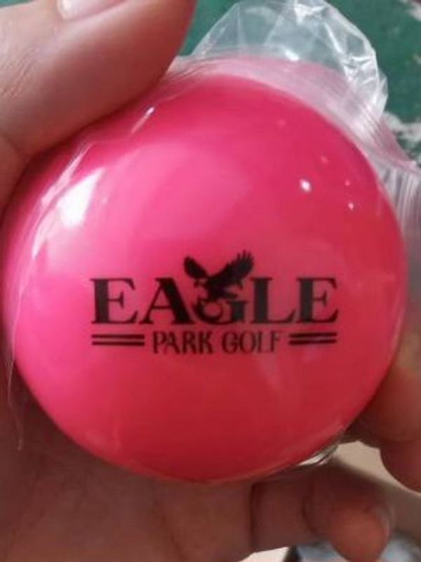 Close-up of a pink golf ball with 'Eagle Park Golf' logo.