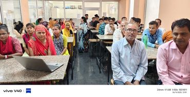 Group of people seated in a classroom setting with a laptop on a desk.
